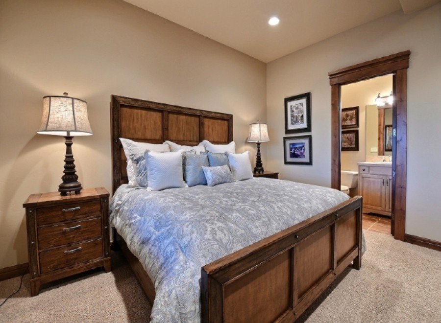 This luxurious bedroom boasts a king-size bed with a plush comforter, complemented by a rustic wooden frame and nightstands.