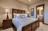 This luxurious bedroom boasts a king-size bed with a plush comforter, complemented by a rustic wooden frame and nightstands.