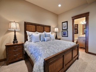 This luxurious bedroom boasts a king-size bed with a plush comforter, complemented by a rustic wooden frame and nightstands.
