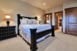 This luxurious bedroom boasts a king-size bed, plush carpeting, and elegant dark wood furnishings.
