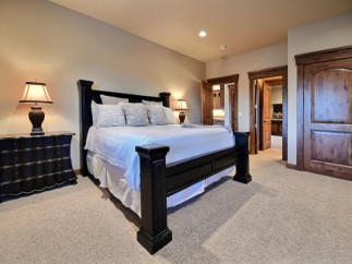 This luxurious bedroom boasts a king-size bed, plush carpeting, and elegant dark wood furnishings.