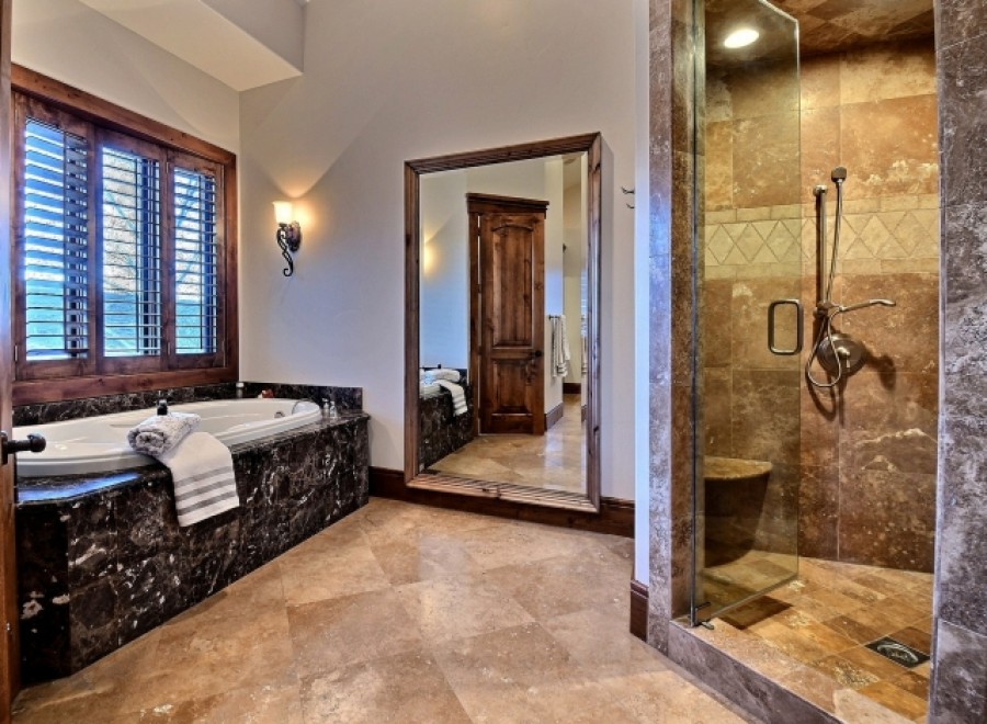 Luxurious master bathroom boasts a large soaking tub and a spacious walk-in shower, both with exquisite stone finishes.