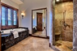 Luxurious master bathroom boasts a large soaking tub and a spacious walk-in shower, both with exquisite stone finishes.
