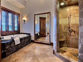 Luxurious master bathroom boasts a large soaking tub and a spacious walk-in shower, both with exquisite stone finishes.