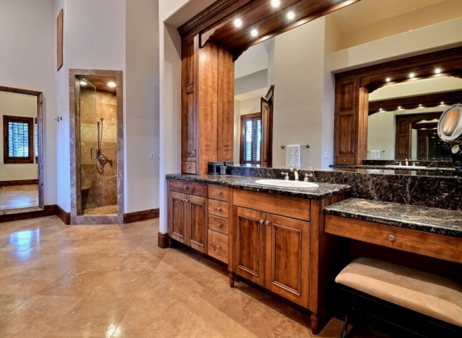 This luxurious master bathroom boasts a spacious double vanity with dark marble countertops and rich wood cabinetry.