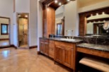 This luxurious master bathroom boasts a spacious double vanity with dark marble countertops and rich wood cabinetry.