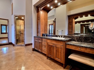 This luxurious master bathroom boasts a spacious double vanity with dark marble countertops and rich wood cabinetry.
