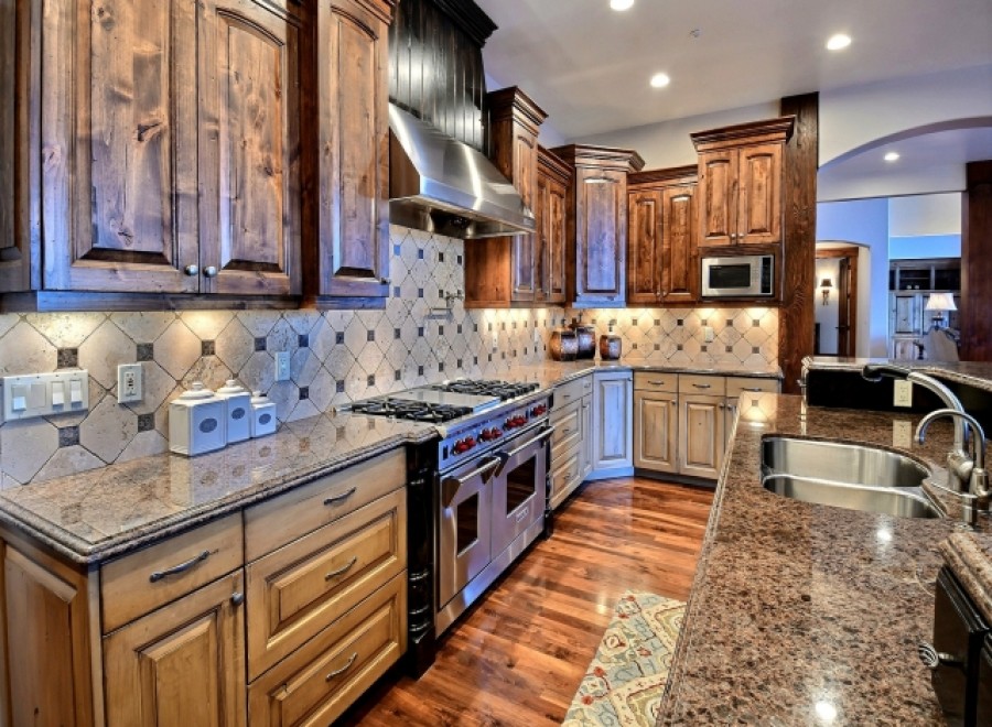 This stunning kitchen boasts beautiful dark wood cabinetry, granite countertops, and high-end stainless steel appliances.