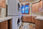 This stunning laundry room boasts a stackable washer and dryer, ample counter space, and rich wood cabinetry.