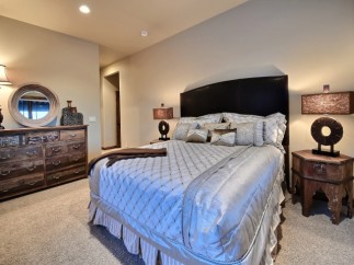 Luxurious master bedroom with a king-size bed, featuring a stunning silver comforter and plush pillows.
