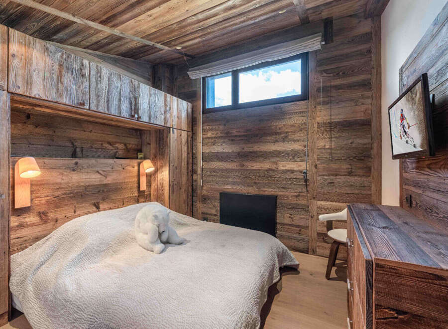 Experience rustic charm in this cozy bedroom, featuring stunning wood paneling and a warm, inviting atmosphere.