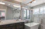 Luxurious bathroom boasts double vanity with quartz countertop and dark wood cabinets.