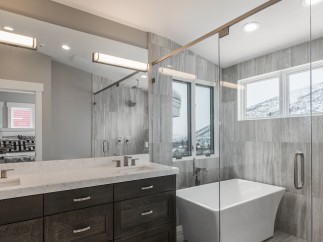 Luxurious bathroom boasts double vanity with quartz countertop and dark wood cabinets.