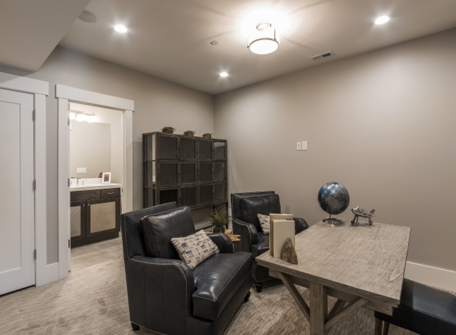 This stunning basement boasts a stylish office space, complete with comfortable leather armchairs and a rustic wooden desk.