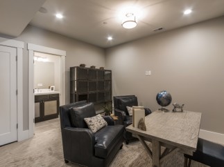 This stunning basement boasts a stylish office space, complete with comfortable leather armchairs and a rustic wooden desk.