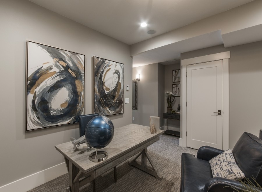 This stunning basement boasts a sophisticated design with gray walls, abstract art, and a stylish workspace.