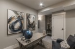 This stunning basement boasts a sophisticated design with gray walls, abstract art, and a stylish workspace.
