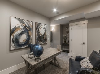 This stunning basement boasts a sophisticated design with gray walls, abstract art, and a stylish workspace.