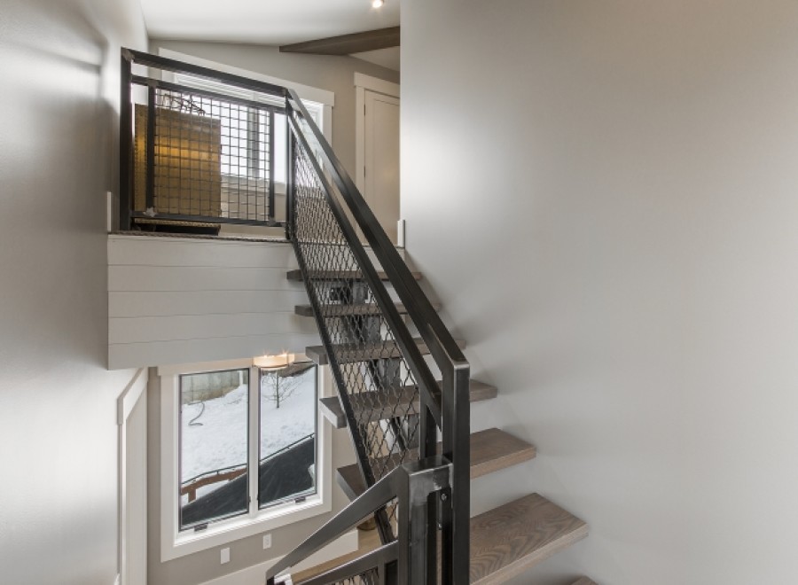 Modern industrial staircase with metal railing and wood steps.
