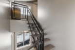 Modern industrial staircase with metal railing and wood steps.