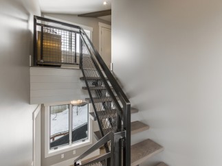 Modern industrial staircase with metal railing and wood steps.