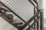 Modern staircase with metal railing and wood steps.