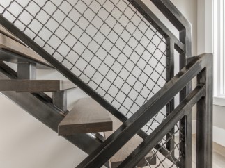 Modern staircase with metal railing and wood steps.
