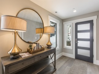This stunning entryway boasts a sleek, modern design with elegant gold table lamps and a sophisticated console table.