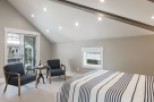 This stunning bedroom boasts a vaulted ceiling with exposed beams, creating an airy and spacious feel.