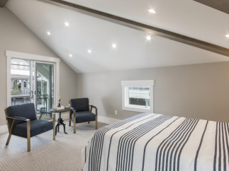 This stunning bedroom boasts a vaulted ceiling with exposed beams, creating an airy and spacious feel.