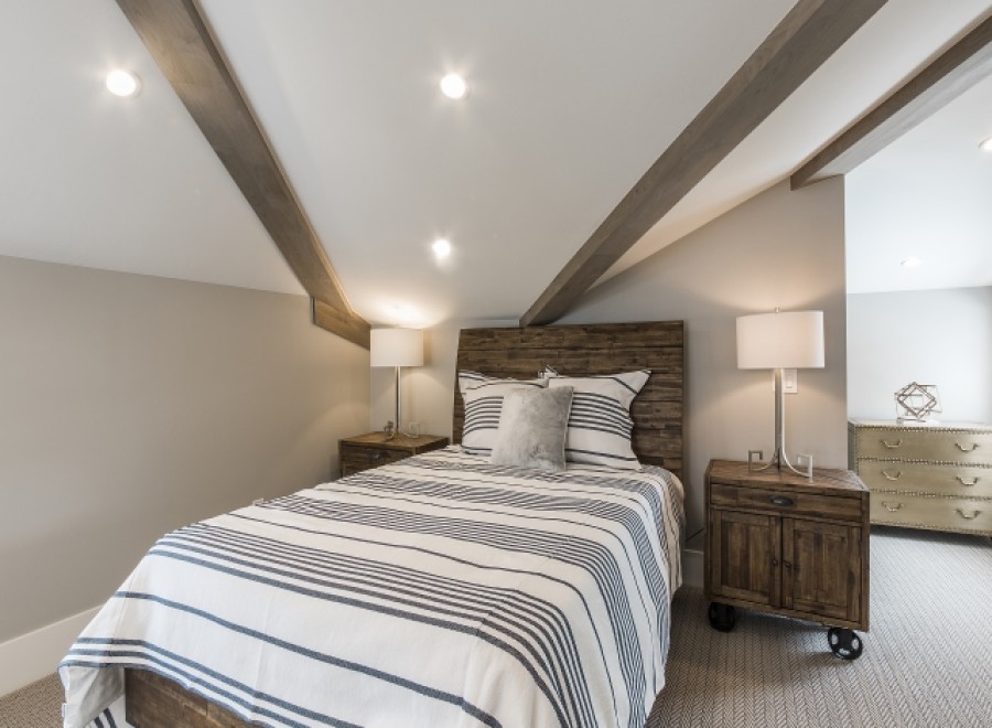 This stunning bedroom boasts a cozy and stylish atmosphere, featuring a comfortable striped duvet and wooden nightstands.