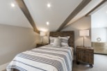 This stunning bedroom boasts a cozy and stylish atmosphere, featuring a comfortable striped duvet and wooden nightstands.