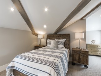 This stunning bedroom boasts a cozy and stylish atmosphere, featuring a comfortable striped duvet and wooden nightstands.