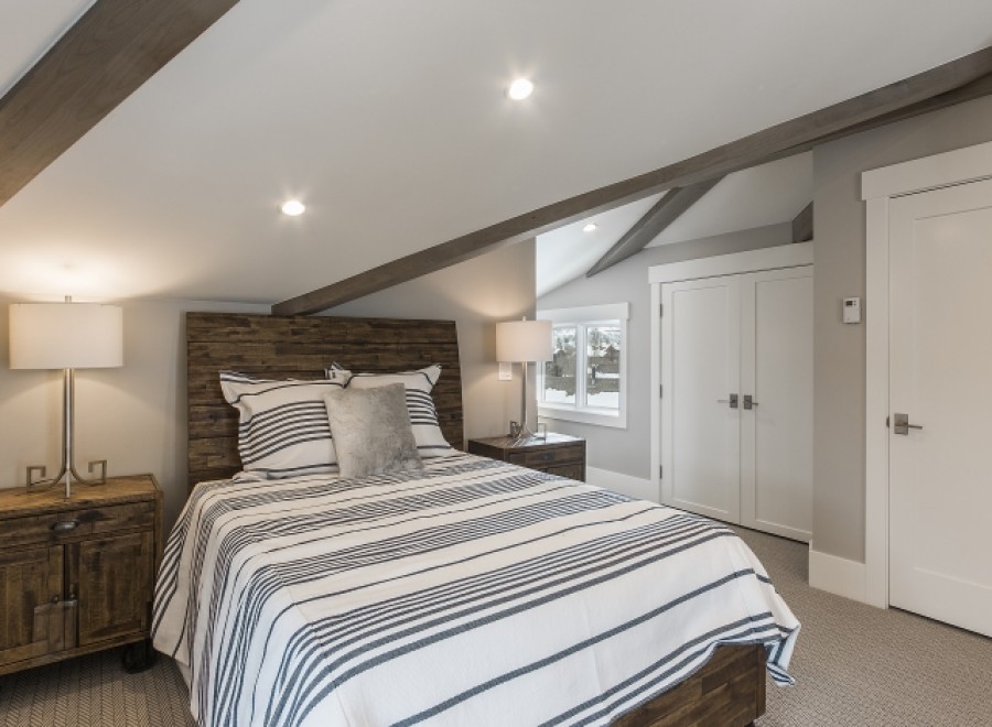 This charming bedroom boasts a cozy atmosphere with its sloped ceilings and exposed wooden beams.