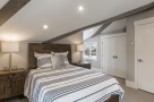 This charming bedroom boasts a cozy atmosphere with its sloped ceilings and exposed wooden beams.