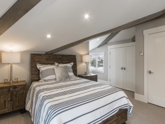 This charming bedroom boasts a cozy atmosphere with its sloped ceilings and exposed wooden beams.