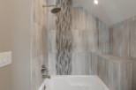 This luxurious bathroom boasts a spacious bathtub and shower combination, complete with modern fixtures and a stunning tile design.
