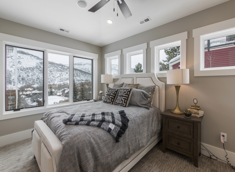 Mountain view bedroom with cozy bedding and large windows.