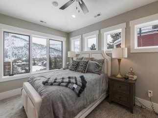 Mountain view bedroom with cozy bedding and large windows.