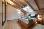 Experience luxury in this stunning bedroom featuring a unique sloped ceiling with exposed wooden beams.