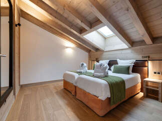 Experience luxury in this stunning bedroom featuring a unique sloped ceiling with exposed wooden beams.