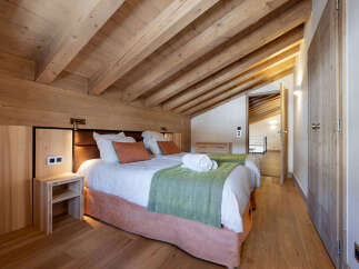Experience the charm of this stunning bedroom, featuring a warm wooden ceiling and walls that create a cozy atmosphere.