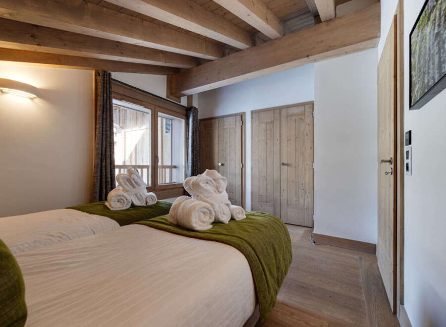 Discover the charm of this cozy bedroom, featuring exposed wooden beams and a warm, inviting atmosphere.