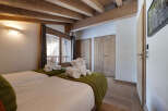 Discover the charm of this cozy bedroom, featuring exposed wooden beams and a warm, inviting atmosphere.