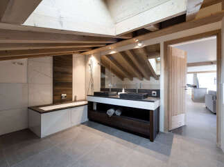 This luxurious bathroom boasts a modern design with a rustic touch, featuring exposed wooden beams and elegant marble tiling.
