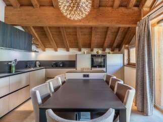 This stunning kitchen and dining area boasts a warm, inviting atmosphere with its exposed wooden beams and modern design.