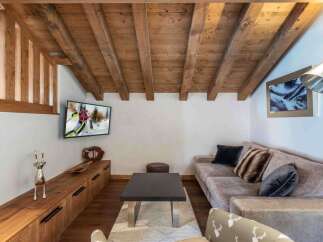 Experience the charm of this cozy living space, featuring a rustic wooden ceiling and a comfortable sofa.