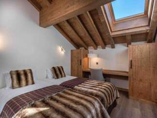 This cozy bedroom features two twin beds with luxurious faux fur throws and pillows, perfect for a comfortable stay.