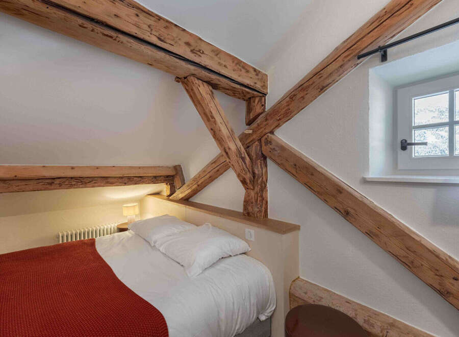 This charming bedroom features exposed wooden beams, adding rustic character and warmth.