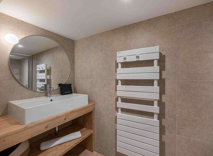 This modern bathroom features a sleek, rectangular sink set atop a rustic wooden vanity, creating a stylish contrast.
